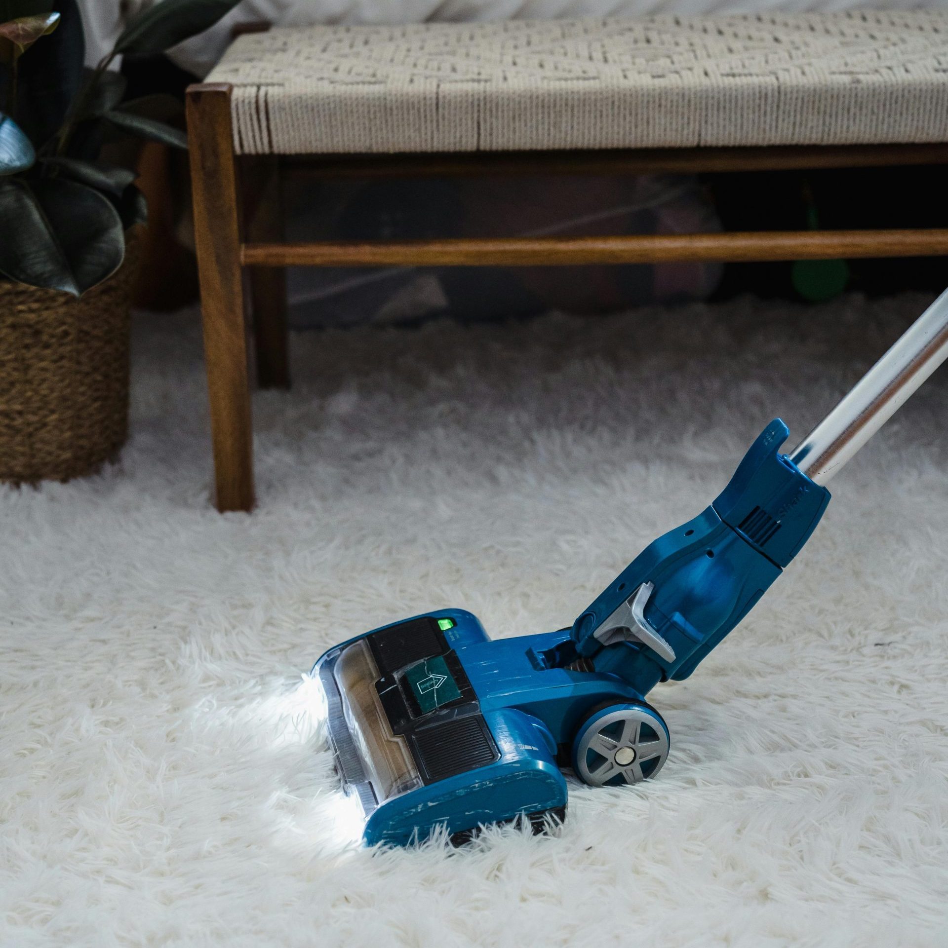 Blue Vacuum Cleaner on White Fur Carpet